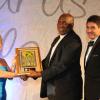 Becky Stockhausen (left), Executive Director of AMCHAM presents the AMCHAM Business & Civic Leadership Award of Excellence, Civic Leadership – Organization awarded to Food For the Poor to Father Burchell McPherson, Chairman of Food For the Poor Foundation.  At right is Ryan Peralto 